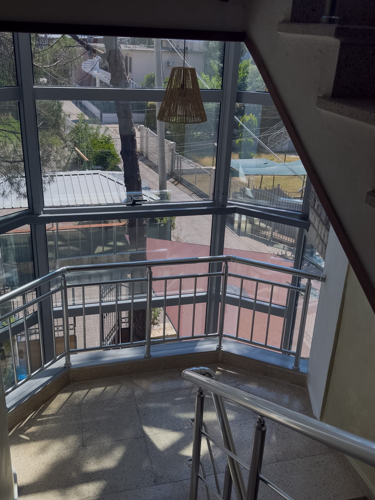 Sunlit hotel stair landing looking toward the street and trees